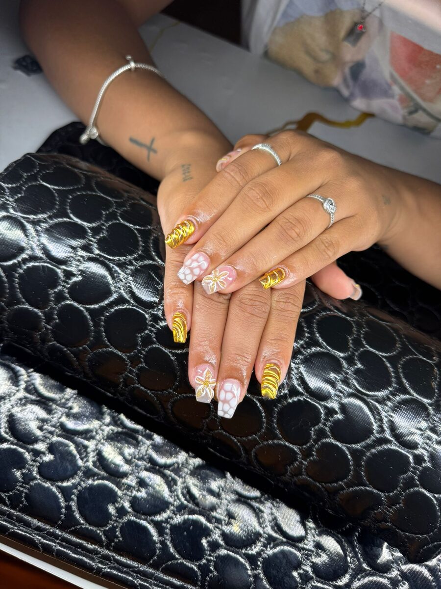 Uñas doradas con detalle floral blanco